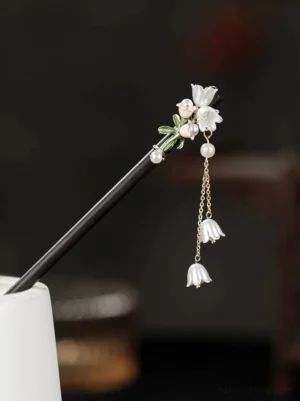 Lily of the valley pearl tassel Chinese hair stick displayed on a white vessel against a dark vintage background