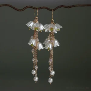 Pair of lily of the valley vintage drop earrings with gold hooks, milky white bell-shaped flowers, long chain tassels, beads, and imitation pearl pendants