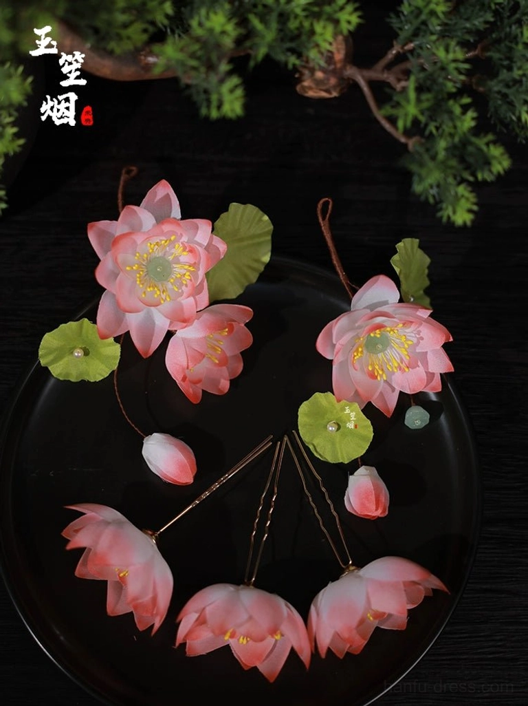 Handmade pink lotus flower Hanfu hair pin set with green leaves bead accents and U-shaped hairpins displayed on a black ceramic plate