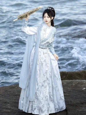 Lingyun blue Ming-inspired Hanfu horse face skirt set worn at a rocky seaside coast with flowing blue draped layers and ink wash printed Mamianqun