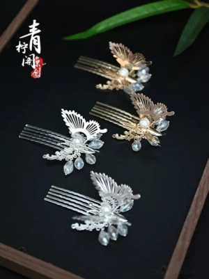 Little Fortune butterfly Hanfu hair pins in silver and gold with faux pearl centers and blue crystal-style drop pendants on a dark wooden tray