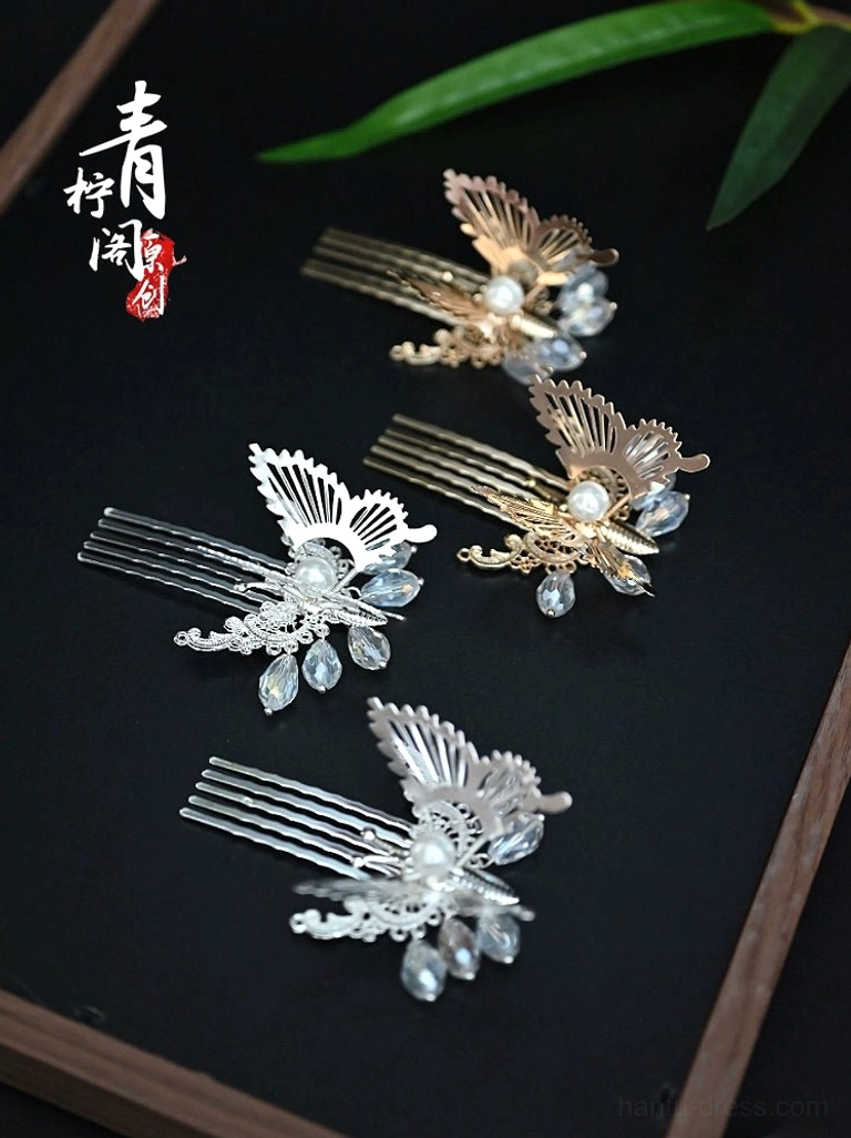 Little Fortune butterfly Hanfu hair pins in silver and gold with faux pearl centers and blue crystal-style drop pendants on a dark wooden tray