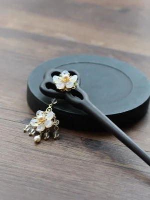 Liuying Hanfu hair stick with white flower and pearl tassel displayed beside matching floral jewelry on a dark tray