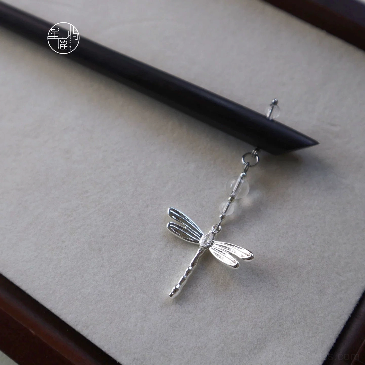 Front view of a long black Chinese hair stick with a realistic silver dragonfly ornament and transparent glass-style beads displayed on a light gray background