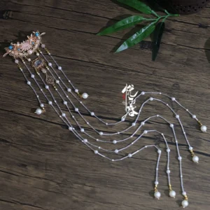 Long tassel Hanfu hairpin displayed on a dark wooden surface with rose gold ornament, beaded strands, pearl drops, and blue decorative accents