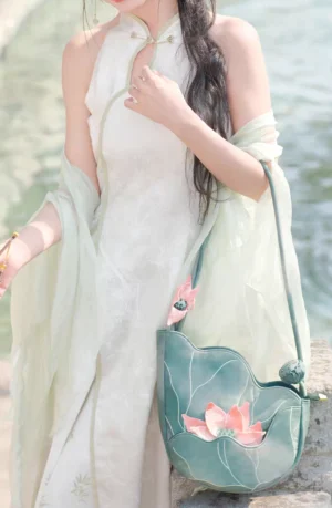 Lotus blossom Chinese shoulder bag styled with a light green modern Cheongsam and sheer shawl in an outdoor waterside setting