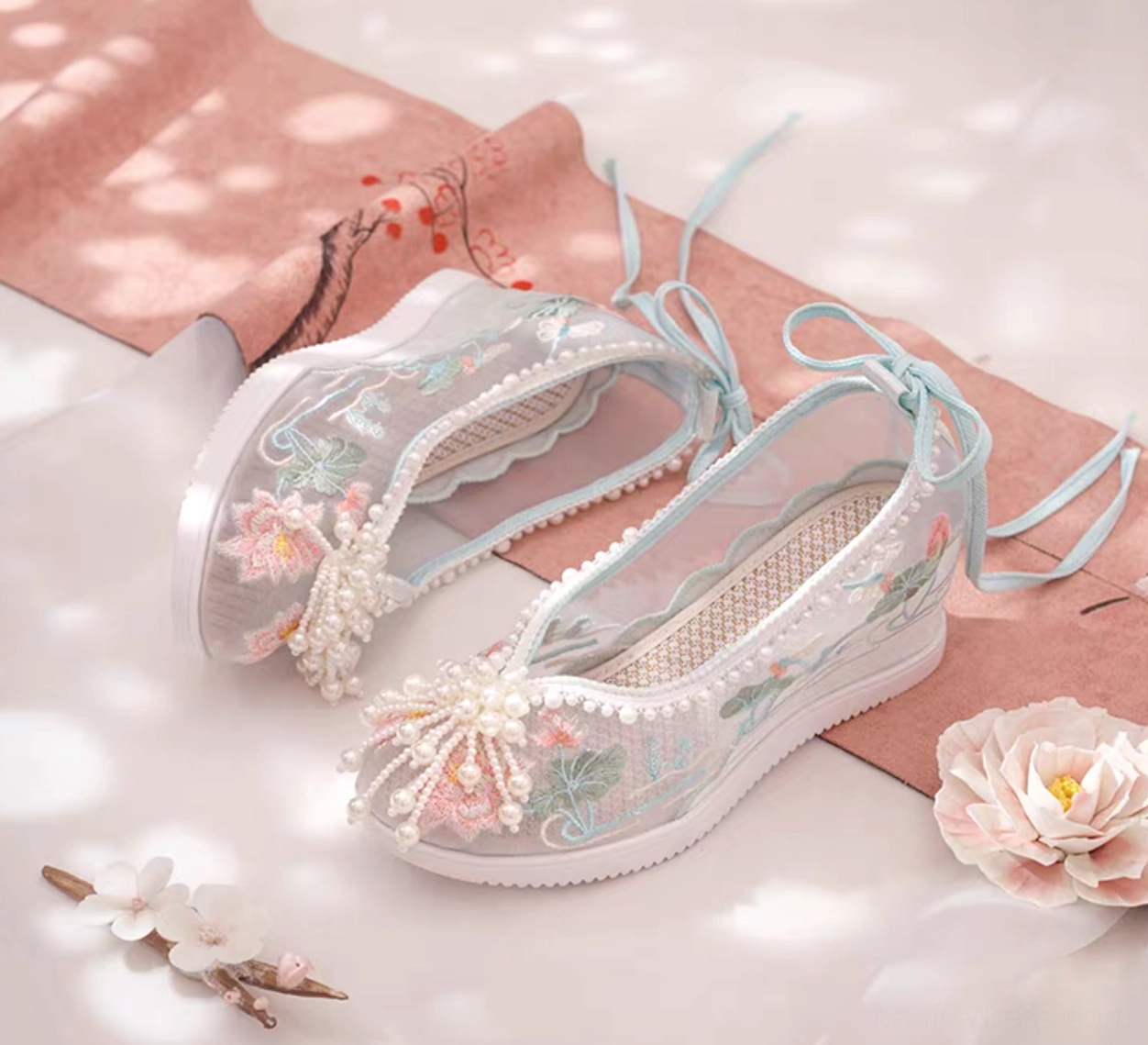 Side view of traditional Chinese Hanfu shoes with lotus floral embroidery, transparent mesh upper, blue ribbons and white wedge sole