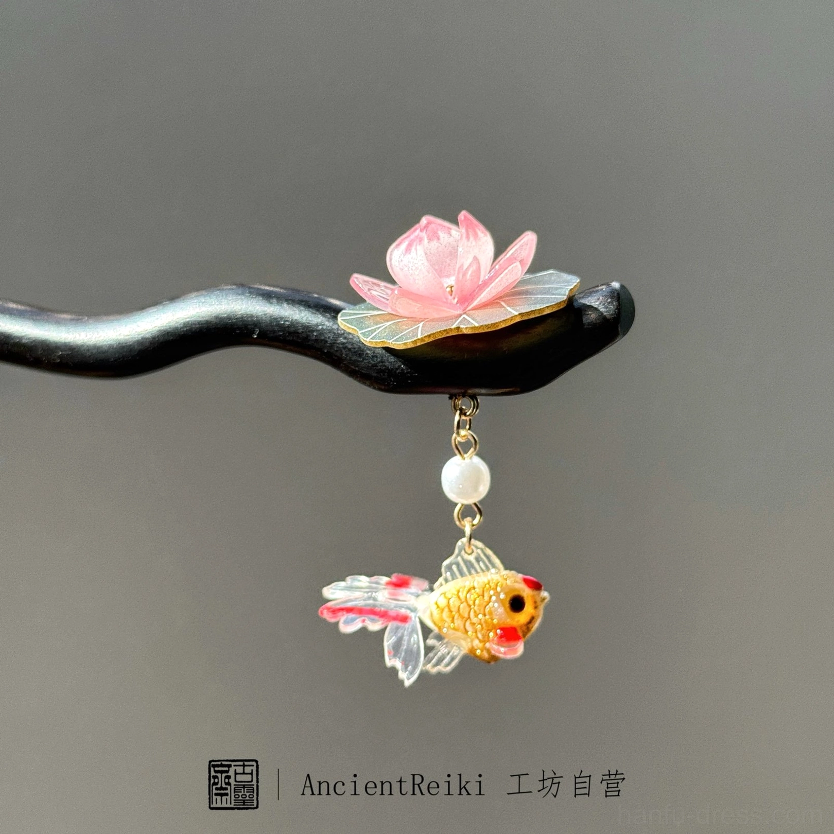 Close-up front-side view of a lotus goldfish Chinese hair stick with a black wooden pin, pink lotus, white pearl, and red-accented golden fish charm