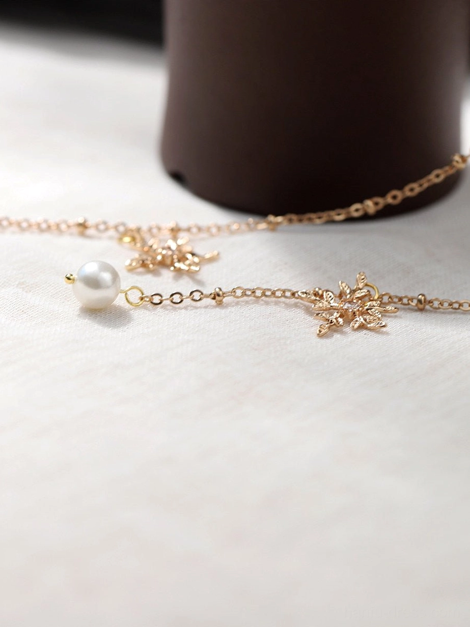 Close-up flat lay of gold-tone tassel chain details with snowflake charms and round pearl pendants for a lotus Hanfu hair stick