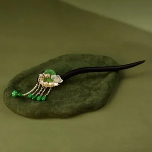 Traditional Chinese lotus hair stick displayed on dark green velvet showing green bead tassels jade accents and pearl details