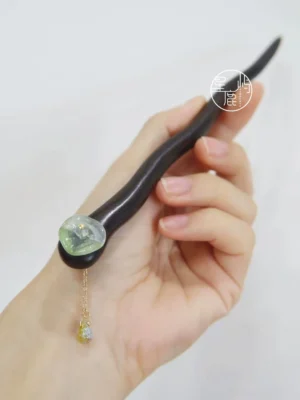 Handheld lotus leaf Hanfu hair stick with curved dark brown shaft, jade-green decorative stone, and delicate gold chain tassel