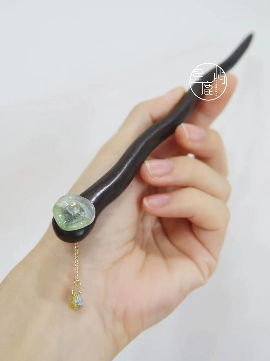 Handheld lotus leaf Hanfu hair stick with curved dark brown shaft, jade-green decorative stone, and delicate gold chain tassel