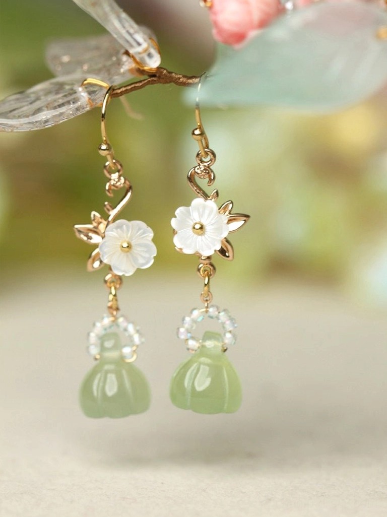 Lotus pod Chinese earrings with white floral charms clear beads and light green pendants arranged with decorative flower branches