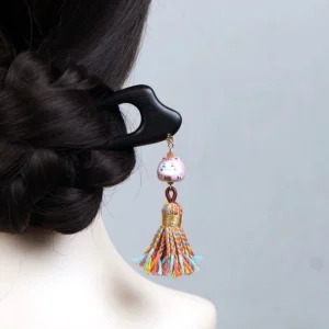 Lucky cat tassel Chinese hair stick worn in a traditional Hanfu coiled hairstyle, featuring a dark wooden double-pronged pin, pink cat charm, and colorful tassel