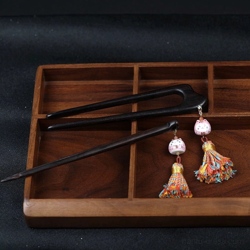 Two lucky cat tassel Chinese hair stick styles displayed on a wooden tray, including single-pronged and double-pronged dark wooden Hanfu hair accessories