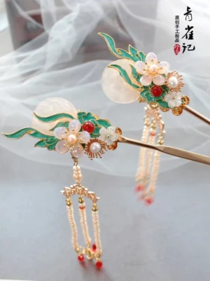 Luna Rain cloisonne moon tassel Chinese hair sticks shown as a pair on white sheer fabric with gold-tone pins green enamel details pearl flowers and red bead drops