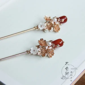 Pair of Luoshen floral Chinese hair sticks with gold-tone flower clusters, white shell-like petals, faux pearls, and red agate-style pendants