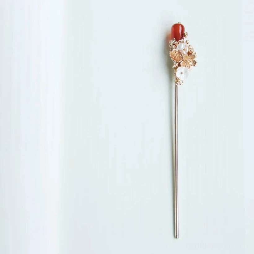 Single Luoshen Chinese hair stick with gold-tone floral ornament, white shell-like petals, faux pearls, and a dangling red agate-style pendant