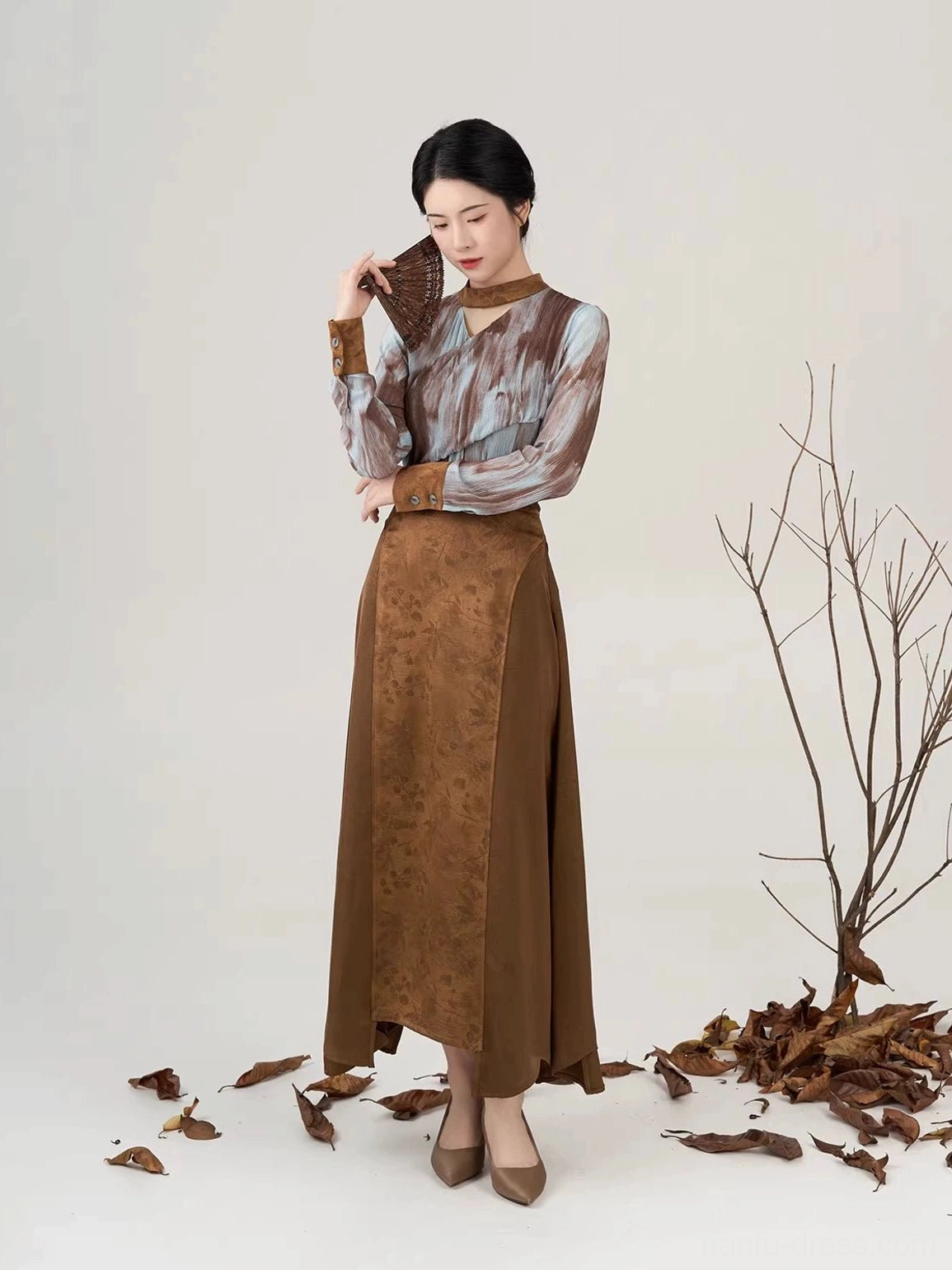 Three-quarter view of Luotong Pass Modern Hanfu outfit with tie-dye top, folding fan, and two-tone brown skirt