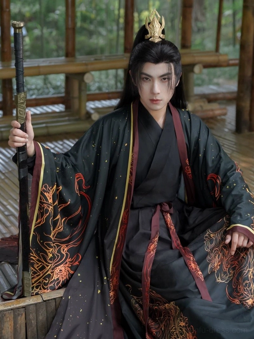 Front three-quarter view of a male Wei-Jin Wuxia Hanfu set with bold red and gold decoration, matching red waist sash, black robe, golden hair crown, and upright sword
