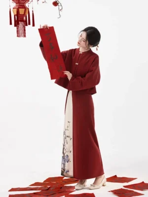 Full-body front view of a maroon Song-inspired modern Hanfu Chinese New Year dress with cropped round-collar top, embroidered wrap skirt, and festive red decorations