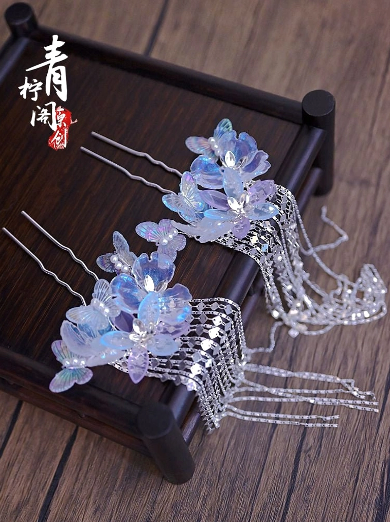 Matching pair of blue purple glazed flower tassel hair pins with silver metal stems and layered crystal tassels on a wooden tray