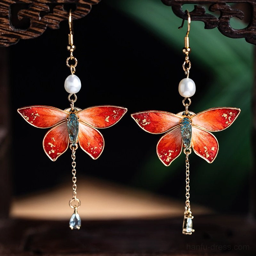 Matching butterfly tassel Chinese earrings with orange-red wings, gold foil detailing, uniform blue teardrop crystals, and freshwater pearl accents