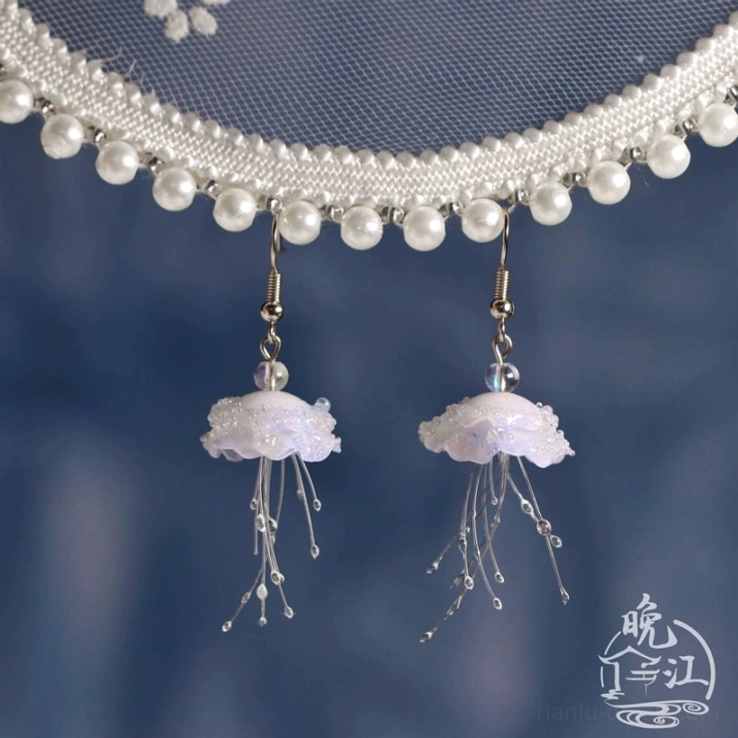 Pair of matching jellyfish Hanfu earrings with gold ear wires and transparent beaded tentacles shown beside pearl details on a deep blue background