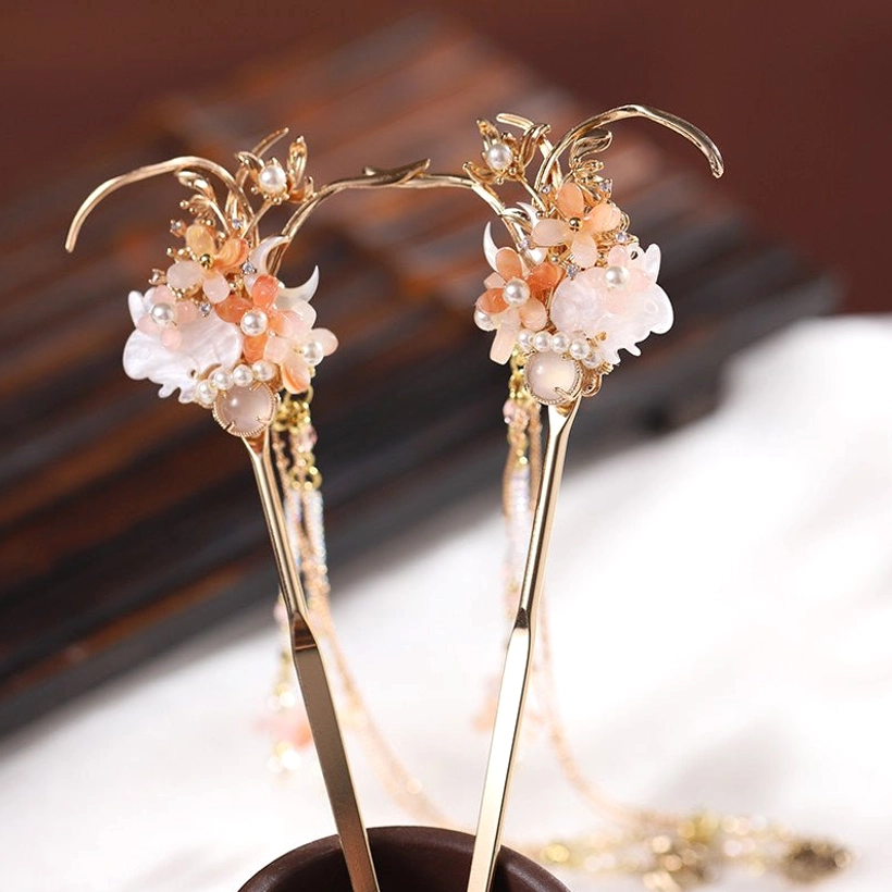 Matching pair of traditional Chinese tassel hair sticks with pink white flowers, pearl details, gold-toned ornaments, and layered chain pendants shown from the side
