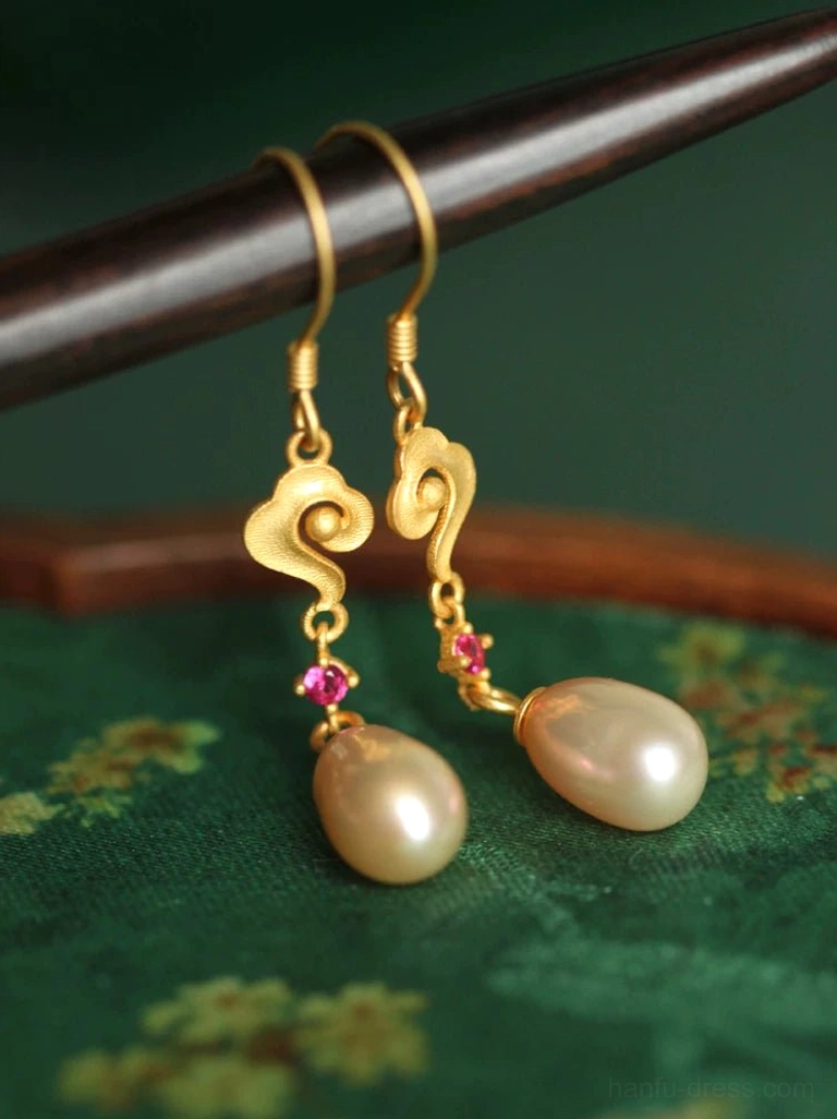 Matte gold cloud pearl drop earrings with rose-red accents and fishhook closures displayed on floral green fabric and wooden tray