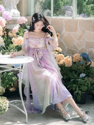 Front three-quarter view of a purple and beige gradient modern hanfu slip dress with embroidered floral bust, flowing chiffon layers, silver heels, and hair accessories