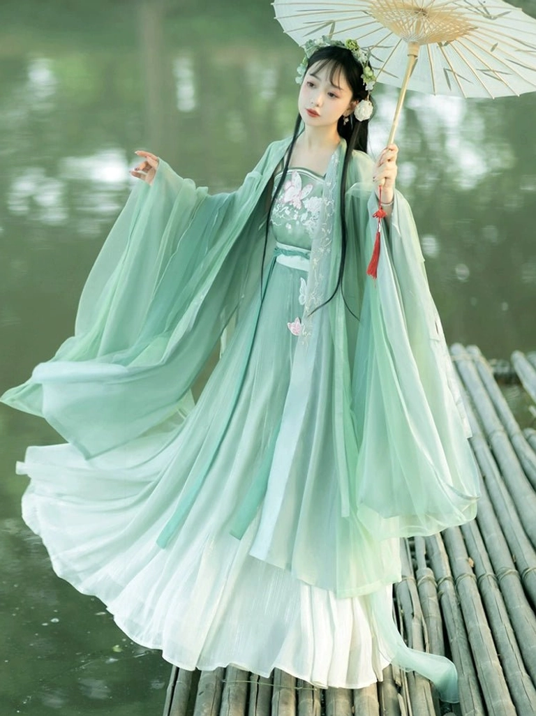 Cyan and ivory Tang Dynasty style qiyao ruqun Hanfu with embroidered floral bodice and wide sleeve outer coat on a bamboo dock