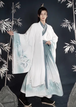 Full-body three-quarter front view of a male model wearing Bamboo Rhyme men's Hanfu with a white to turquoise gradient, printed bamboo leaves, cross-collar top, wrap skirt, and wide-sleeved outer robe