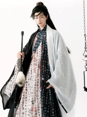Men's black and white calligraphy hanfu robe and outer coat styled with a traditional writing brush in an artistic studio setting