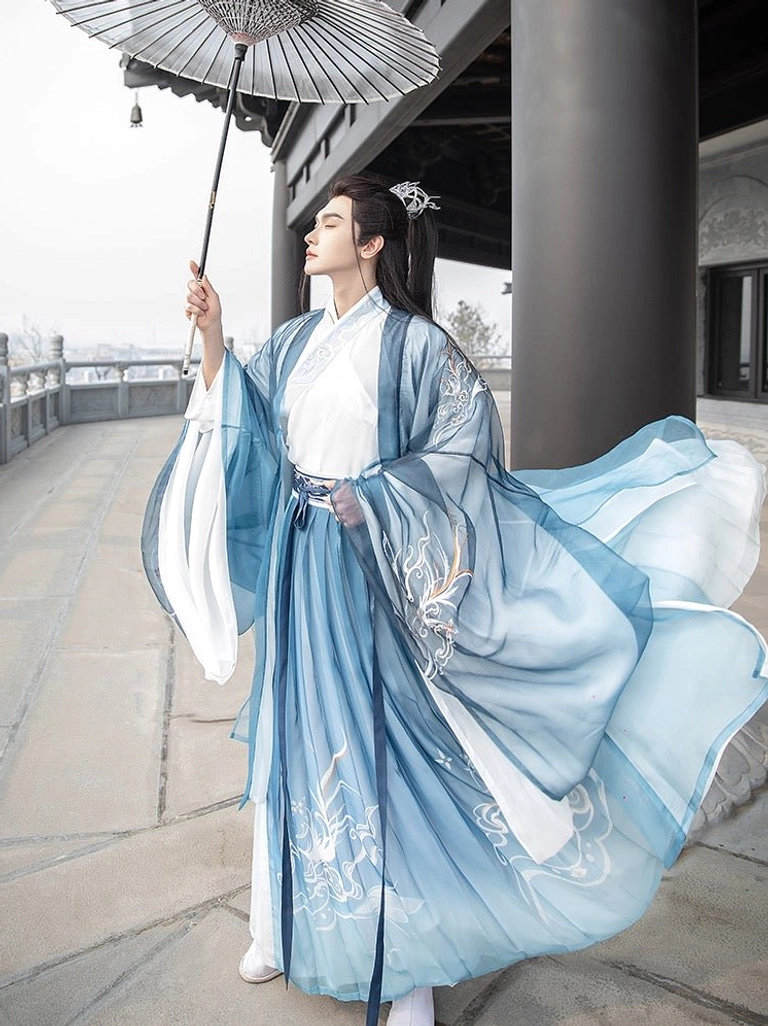 Men's blue gradient wuxia Hanfu with cross-collar top wide sleeves and delicate cloud embroidery styled with an oil-paper umbrella on a pavilion corridor