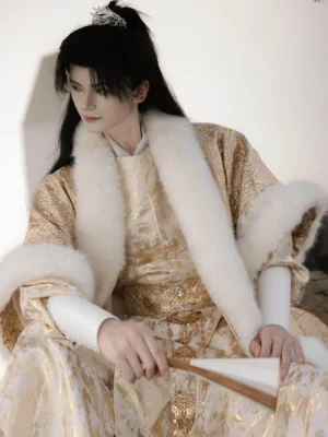 Male model wearing a champagne gold Tang Dynasty men's hanfu robe with white faux arctic fox fur coat trim, traditional hairstyle, hairpin, ornate waist accessory, and folding fan