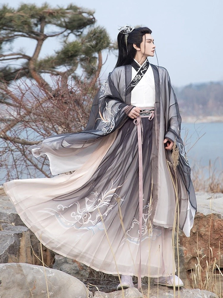 Dark gradient male Hanfu with flowing wide sleeves silver floral and cloud embroidery and pink waist sash styled in a rocky lakeside landscape