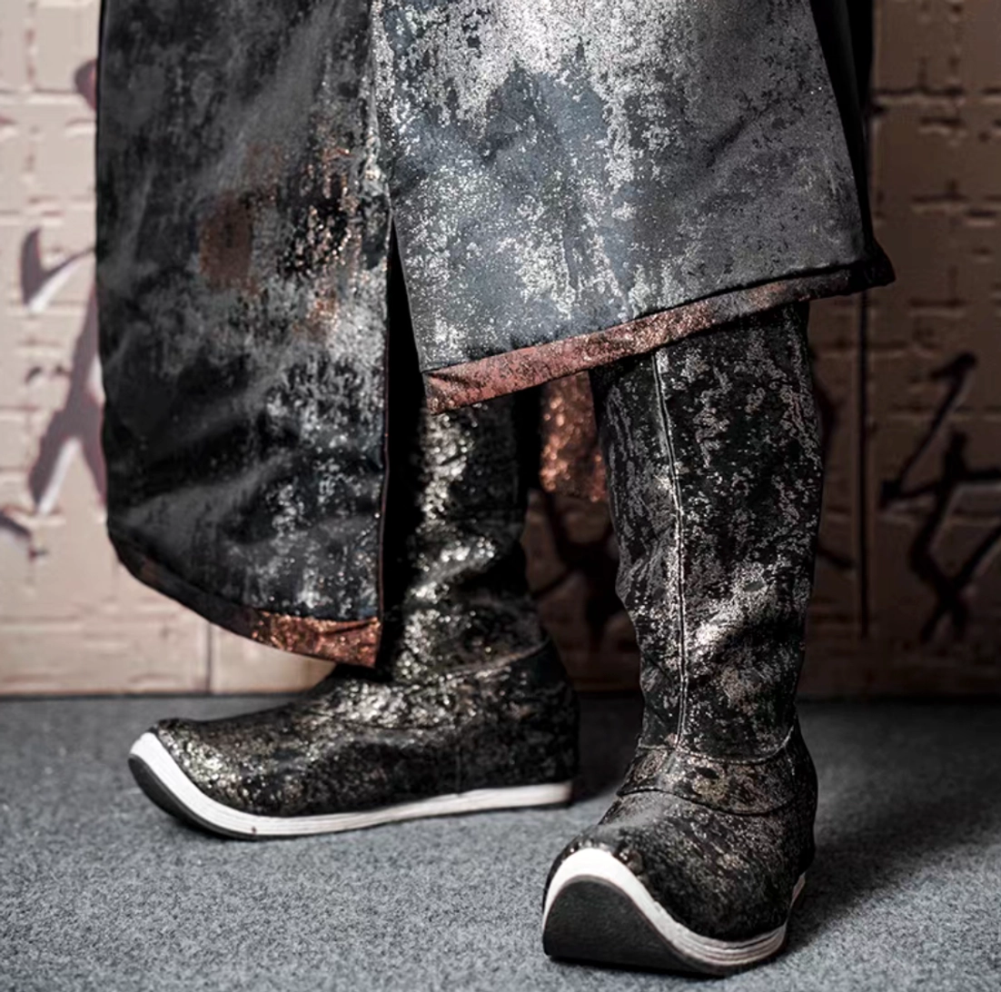Men's dragon scale traditional Chinese Hanfu high-top boot shown in close-up with distressed metallic black silver and bronze texture, upturned rounded toe, white sole edge, and long Hanfu robe