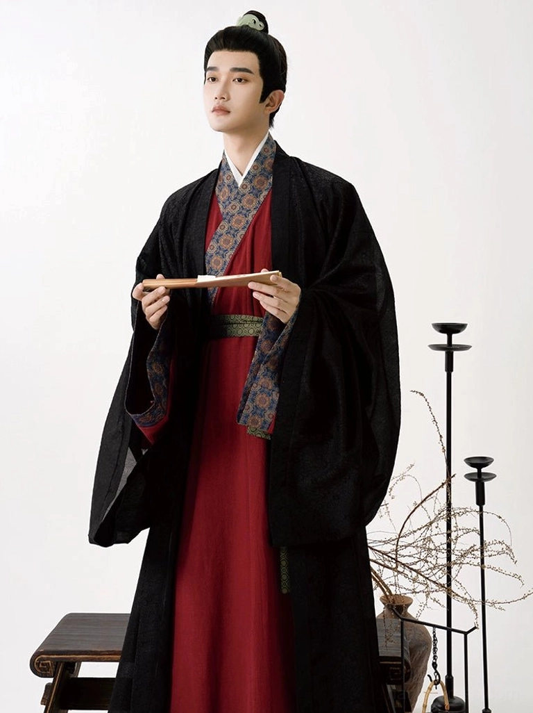 Close-up of male Song Dynasty hanfu featuring a textured black outer robe, rich burgundy cross-collar inner robe, ornate patterned collar trim, and dark green fabric waist belt