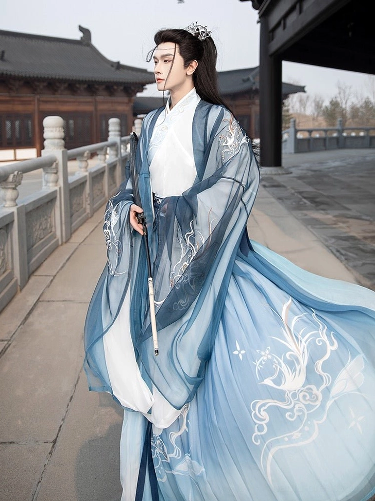 Heather blue male Hanfu Qiyao Ruqun with silver patterned waistband and layered flowing robes styled with a sword beside a traditional courtyard railing