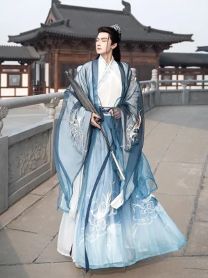 Heather blue men's wuxia Hanfu Qiyao Ruqun set with flowing gradient robes and silver mythical bird embroidery worn in a traditional Chinese courtyard