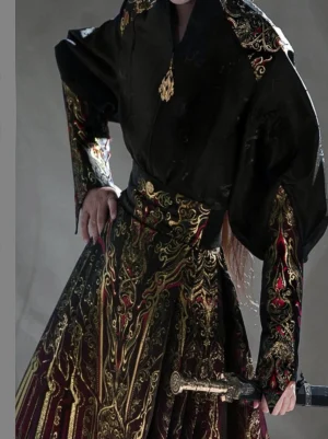 Close-up front view of a modern Chinese hanfu top with black satin fabric, gold embroidered shoulder decorations, patterned cuffs, wide waistband, and red gold skirt details