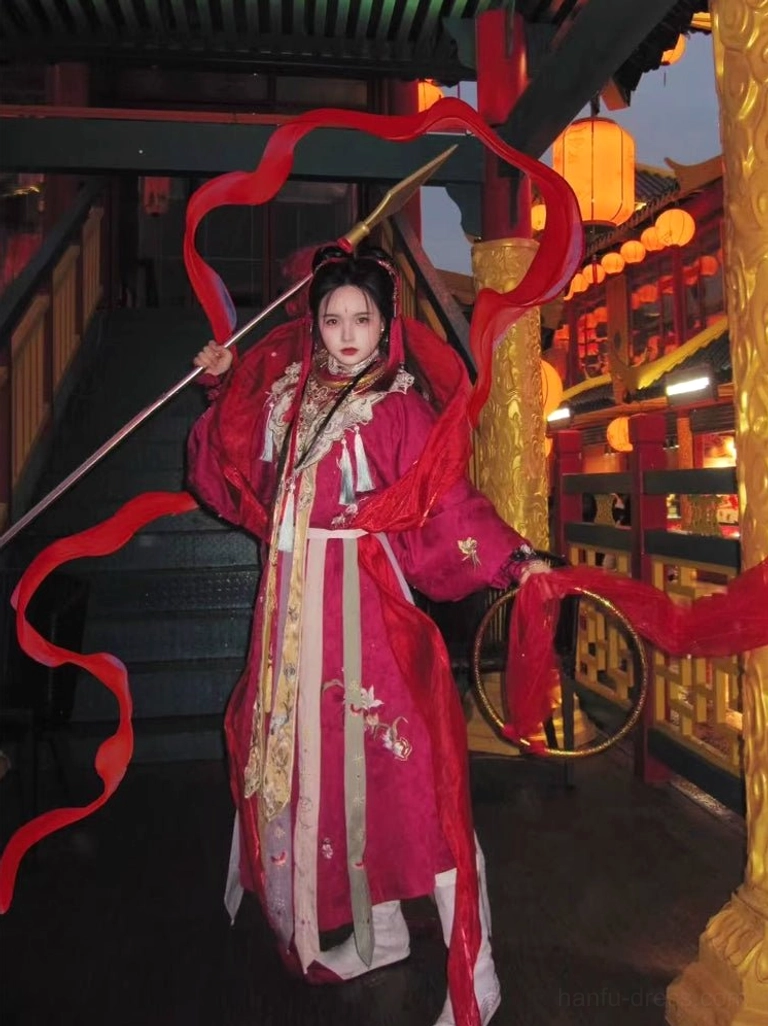 Men's Nezha Chinese immortal costume in a deep red robe with gold embroidery layered waist sashes and traditional architecture background