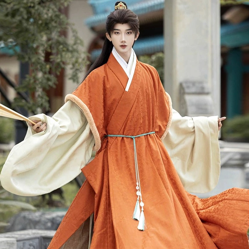 Close up of burnt orange men’s Ming Dynasty Hanfu outer robe showing cross collar cream lining fuzzy cuff trim tassel belt and jacquard texture