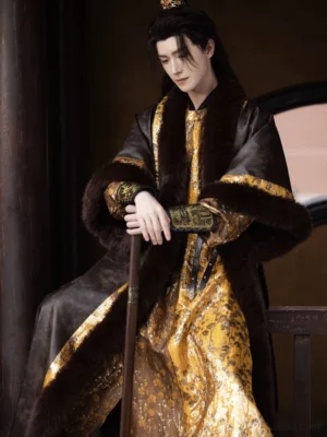 Three-quarter front view of a men's Tang Dynasty Hanfu set showing the luxurious gold brocade robe, dark fur collar, fur-trimmed sleeves, and decorative wrist cuffs in a traditional corridor