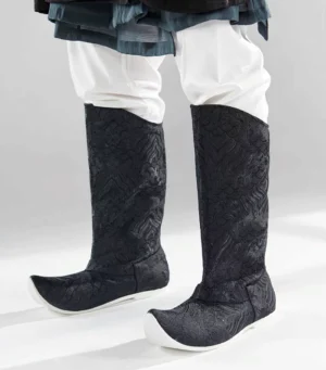 Front view of men's traditional Chinese Hanfu boots with dark embossed brocade uppers, curved shaft edges, upturned toes, and contrasting white rubber outsoles