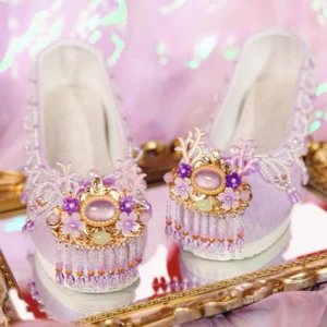 Front three-quarter view of purple traditional Chinese Hanfu shoes with beaded edging, jeweled gold floral ornaments and dangling crystal tassels