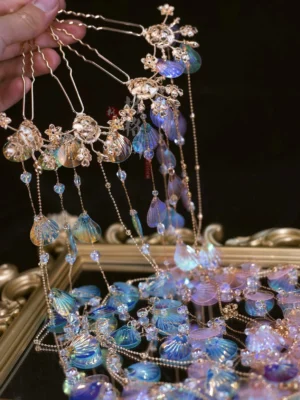 Close-up of iridescent blue purple mermaid shell tassel Hanfu hair pins with gold flower mounts and delicate beaded chains held in hand