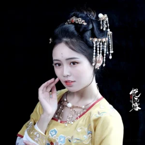 Woman wearing a pearl tassel Hanfu hairpin with blue accents and red details in a traditional Tang-style hairstyle and Hanfu outfit