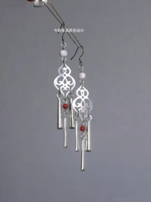 Miao-inspired Chinese Hanfu gourd tassel earrings displayed on a jewelry stand, featuring hollow carved silver-toned pendants, white round beads, red accent beads, and long dangling metal tassels